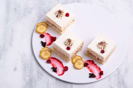 A serving of delicious fruit vanilla cake pieces on a white plateの写真素材