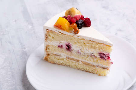 A top view shot of sliced white fruit cake on a white plate