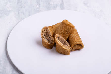A plate of stuffed pancakes with meat on a white tableの写真素材
