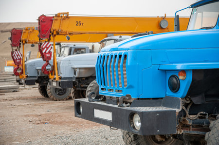 A closeup row of large truck cranes and machines at an industrial construction siteの写真素材