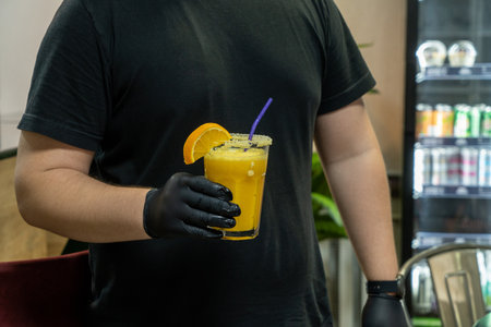 A closeup of the bartender holding a glass of orange drink in sports complexの写真素材