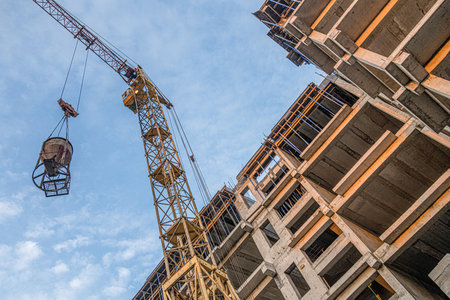 A low angle shot of a crane with equipment on a construction site with a new building infrastructure. Pouring concrete into a moldの写真素材