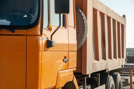 A closeup of an orange dumper truck in an construction areaの写真素材