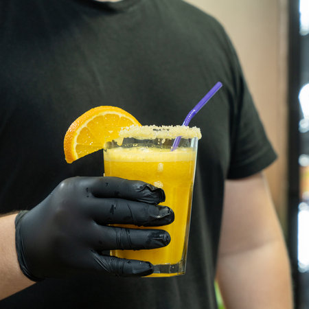A vertical closeup of the bartender holding a glass of orange drink in the sports complexの写真素材