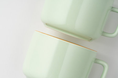 A set of white and pastel green ceramic teacups with orange outlinesの写真素材