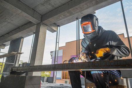 A working welder makes a metal structure in a new building infrastructure