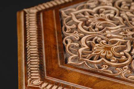The close-up vintage oriental wooden table with the artistic carving on a black background,...