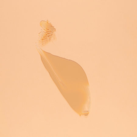 Smear of brown cream for face and body on a sand color backgroundの写真素材