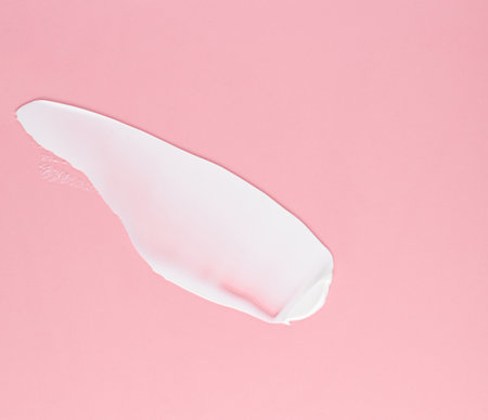 Smear of white cream for face and body on a pink backgroundの写真素材