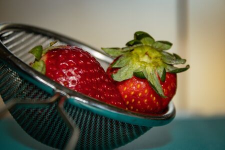 Macro photo of red strawberries inside a metal strainerの写真素材