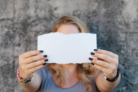 teenage girl in casual clothes holding blank sheet of paper