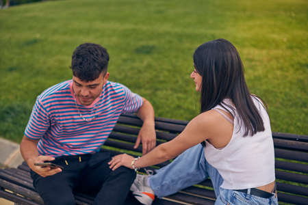 young couple looking at mobile phone and talking to friends wearing face maskの写真素材