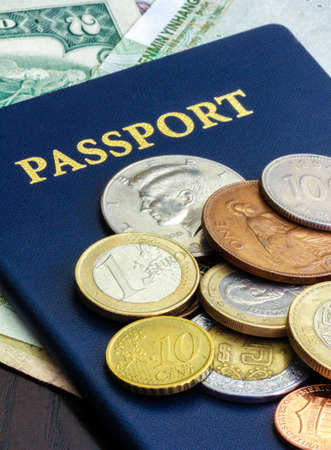 Blue passport with world currency on dark wood tableの写真素材