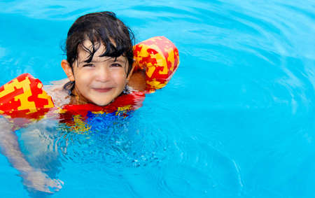Cute little girl with hazel eyes and enjoy her time in the swimming poolの写真素材