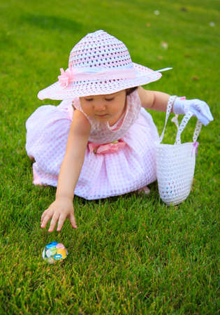 A beautiful little girl in a delightful Easter-themed dressed enjoying the Easter Egg Hunt while...