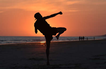 a fighter training on the beach at sunsetの写真素材