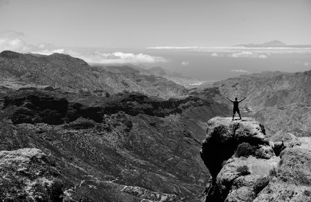 Man on top of a mountain with a view of the sea.の写真素材