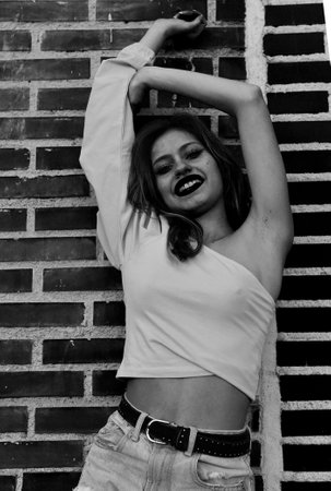 young beautiful latin woman in the city, on the street, against a brick wallの写真素材