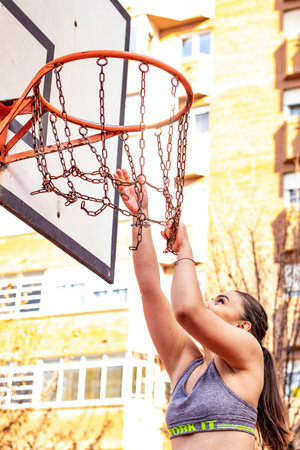 A Caucasian basketball player is smiling as she tries to grab a basketball hoopの写真素材