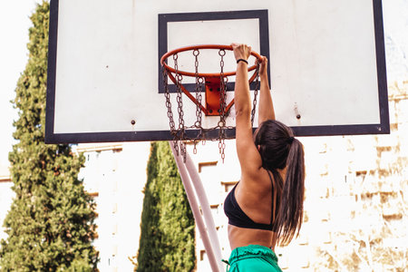 A brown-haired Caucasian basketball player hangs herself from the basketball hoop