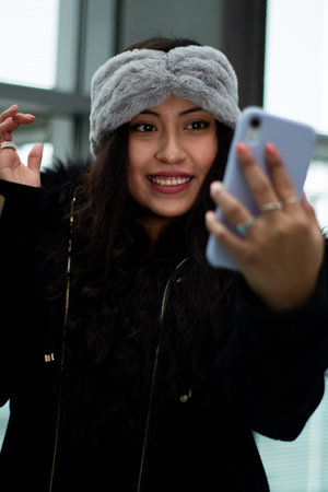 Latina girl is shopping in a mall, she smiles and looks at her cell phone.の写真素材