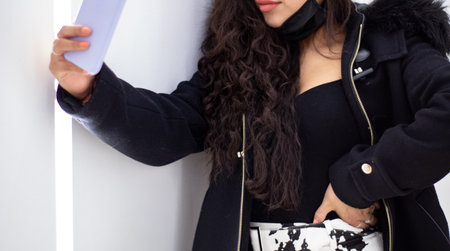 body and face of a Latina girl taking a selfie in a brightly lit aisle of a shopping mall.の写真素材
