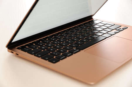 Gold laptop, incredibly thin, light and perfectly portable notebook open with blank white screen on...