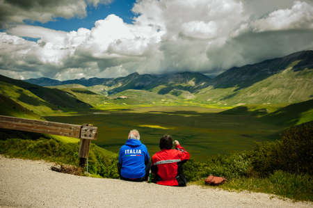 Castelluccio di Norcia, Umbria, Italy - June 21, 2020: biker couple admires the spectacular panorama of the Piano Grande in the Sibillini mountains.のeditorial素材