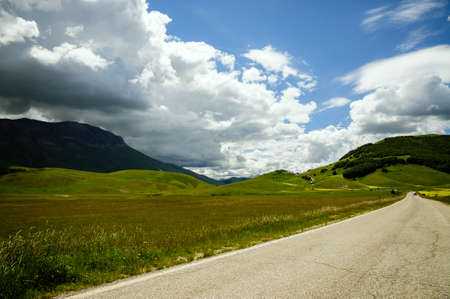 Beginning of flowering of Castelluccio di Norcia (June 2020): fields in lavish color, the small town on the hill and Monte Vettore in the background.の写真素材