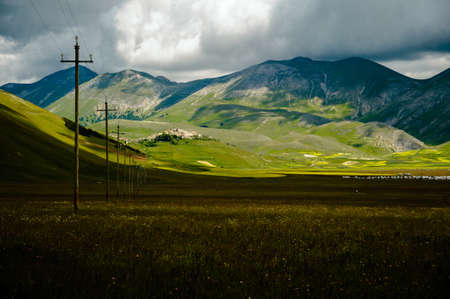 The beginning of flowering in the Piano Grande near Castelluccio di Norcia (June 2020): fields in lavish color, with the small town on the hill.の写真素材