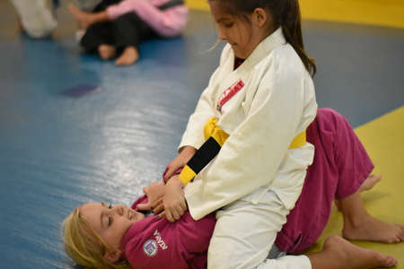 Two kids fighting jiu jitsu on mat using pink and white giのeditorial素材