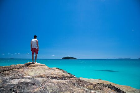 Man standing on a cliff contemplating the horizon