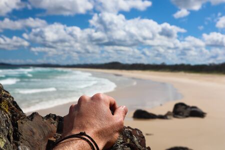 Close up of a man's hand with beach in the backgroundの写真素材