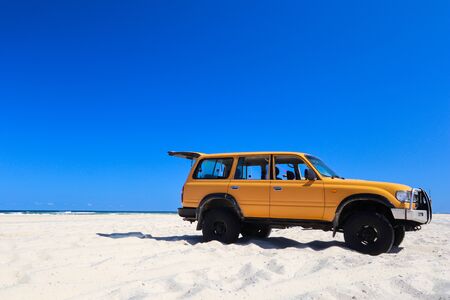 Car parked on the beach against a clear blue skyの写真素材