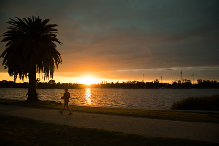 Silhouette of a man doing sports by the river at sunset