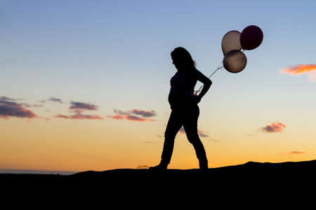 Pregnant girl silhouette walking over some dunesの写真素材