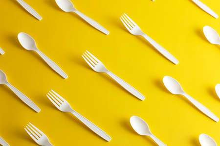 Disposable plastic cutlery forks and spoons forbidden for pollution of the environment yellow backgroundの写真素材