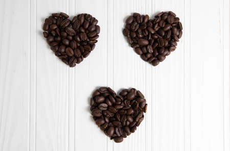 Three heart shape coffee beans in over a wood backgroundの写真素材