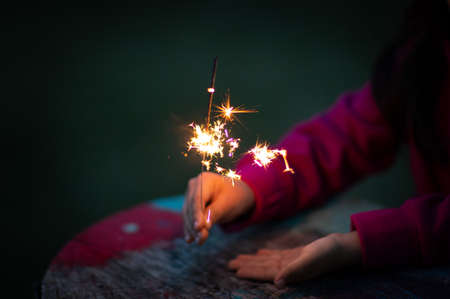 Kid holding a brilliant sparkler during nightの写真素材