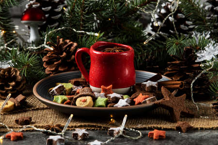 Hot tea on a red cup and Christmas cookies with a star and snowman shape. Decorated with natural...