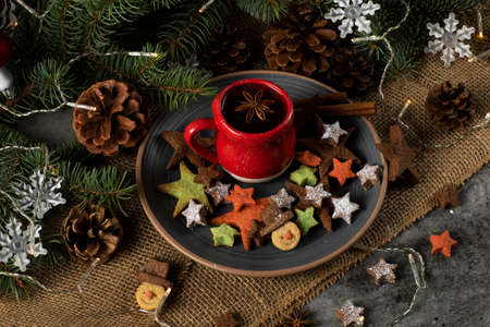 Hot tea on a red cup and Christmas cookies with a star and snowman shape. Decorated with natural pine branchesの写真素材