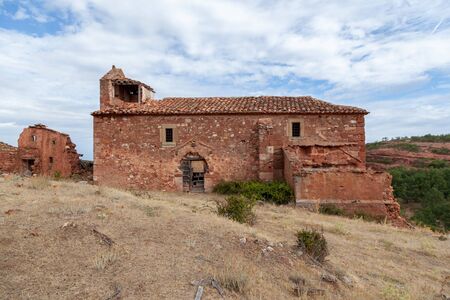 Ruins of an ancient church of red stone and a broken door of woodの写真素材