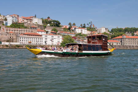 Porto, Portugal - May 14, 2011: Changed Rabelo ship carrying tourists between the bridges of the river Douro showing the riverside area of ââPorto and Vila Nova de Gaia.のeditorial素材