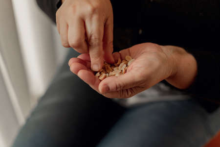 Detail of the hands of an adult woman holding a bunch of peanuts and taking them with her right hand