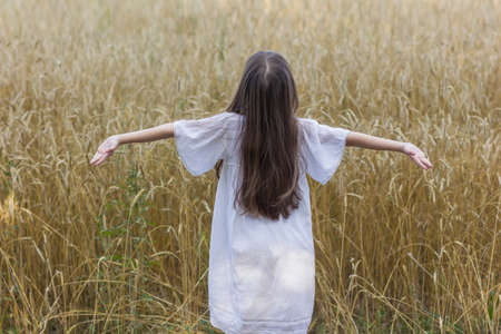 summer holidays, vacation and people concept - happy young girl in white dress on cereal fieldの写真素材