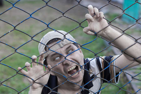 creepy zombie screams and climbs the iron netの写真素材