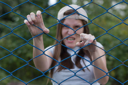 creepy zombie screams and climbs the iron netの写真素材