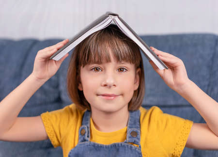 little girl holding a book under her head and smiles