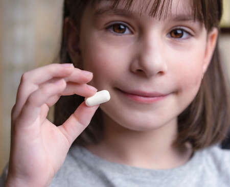 A child holds a white tablet. Medicines and synthetic vitamins. The concept of drug selection. treatment for children.の写真素材