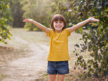 Young child arms raised up to the sky, celebrating freedom. positive children emotions. Free smiling girl in summer forest enjoying nature. happy life conceptの写真素材